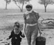 Photograph of a mother and son crossing a drought-effected paddock. Photograph of a mother and son crossing a drought-effected paddock.