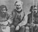 Photograph of Angus McMillan sitting with two Aboriginal men. Photograph of Angus McMillan sitting with two Aboriginal men.